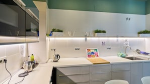 A modern kitchen with white cabinets, a stainless steel kettle, and a wooden countertop. - The Book Factory Hostel by gaiarooms (Valladolid)