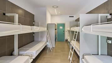 Un dormitorio con literas, una puerta y una lámpara.