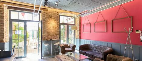 Un interior moderno con una pared de acento roja, una mesa de centro de vidrio, sofás de cuero y una pared de ladrillo.