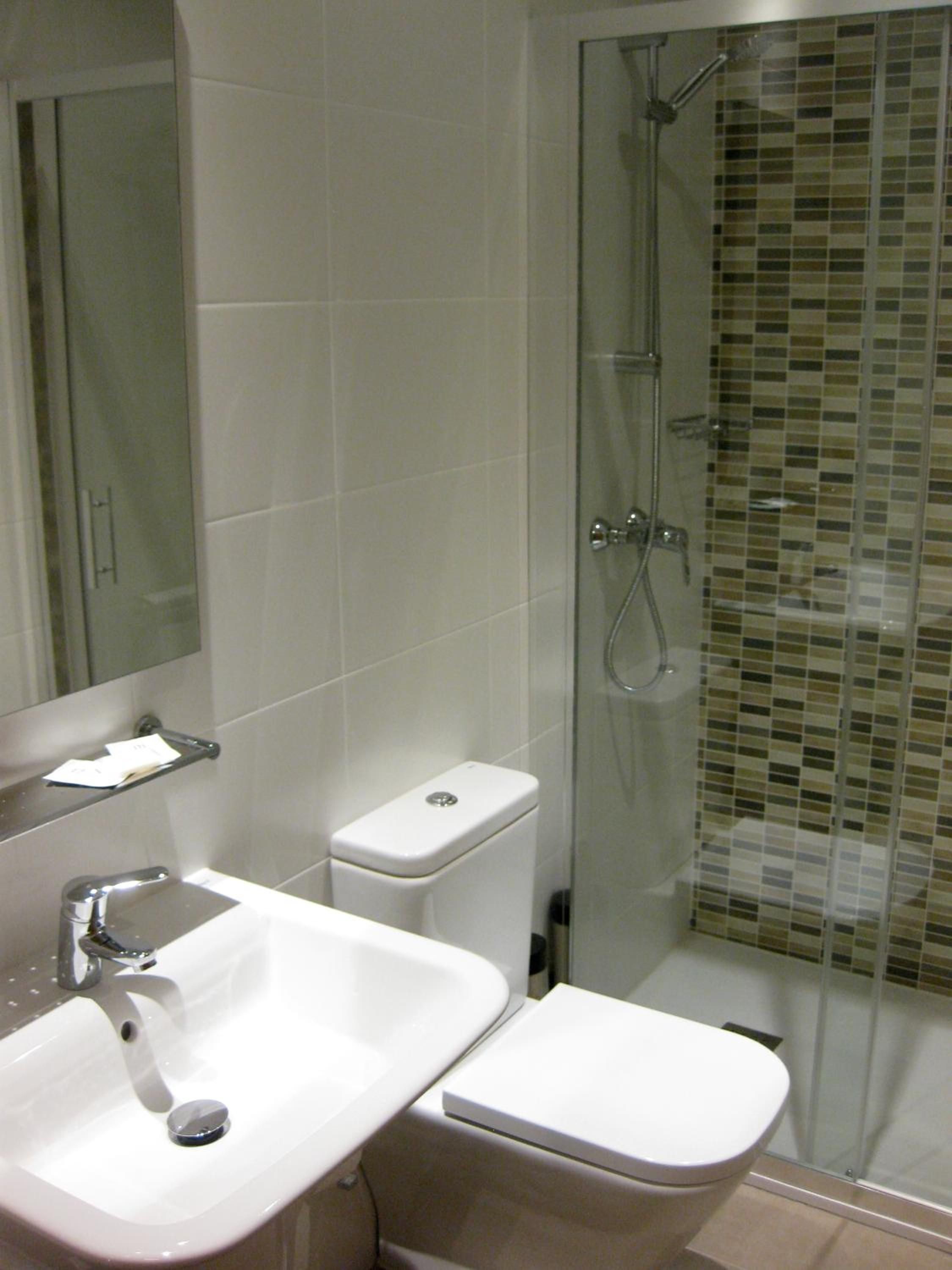 A bathroom with a white sink, a toilet, and a glass-enclosed shower area.