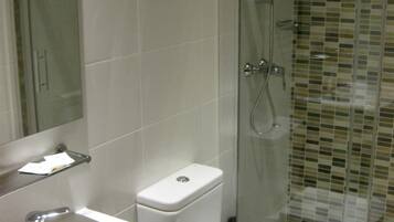A bathroom with a white sink, a toilet, and a glass-enclosed shower area.