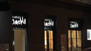 Exterior de un edificio con tres letreros iluminados que dicen 'El Café de Amable'.