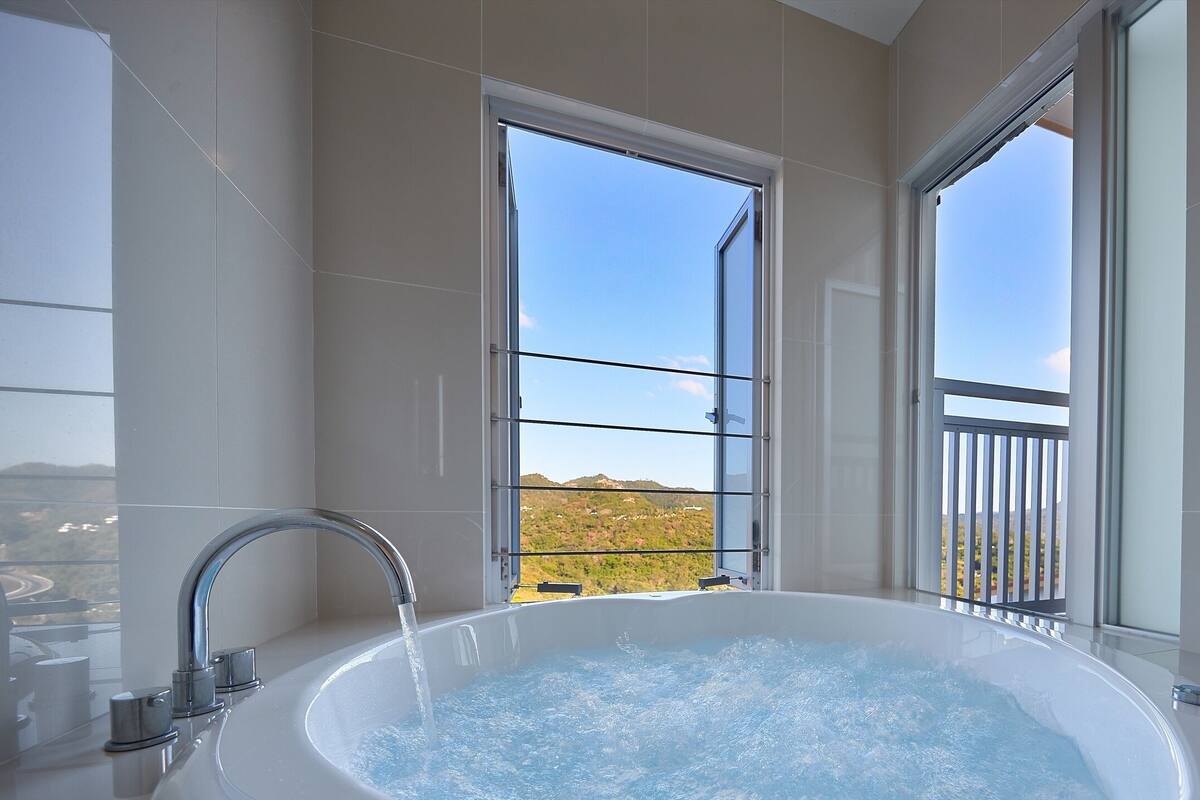 Une salle de bain moderne avec une grande baignoire, un robinet et une fenêtre donnant sur un paysage.