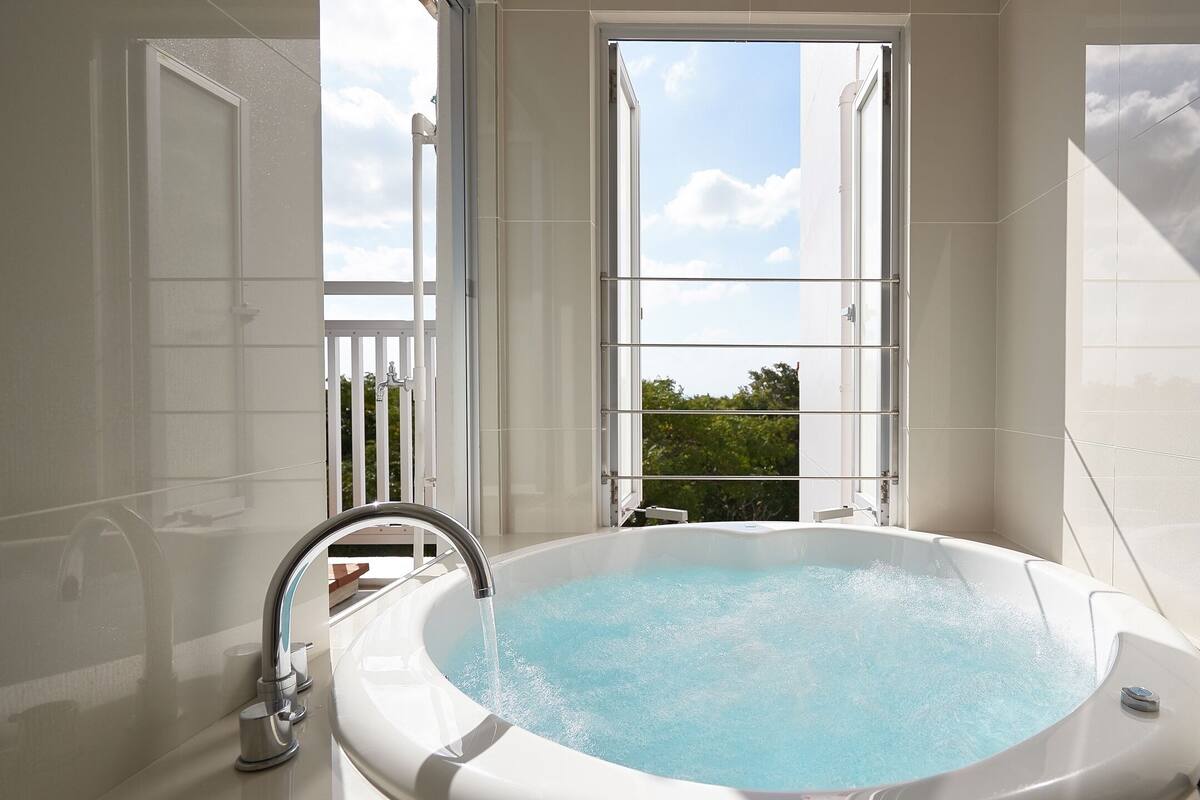 Une salle de bain moderne avec une baignoire sur pieds, une fenêtre offrant une belle vue et des articles de toilette à portée de main.
