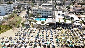 A beach with numerous umbrellas and sun loungers, a swimming pool, and buildings in the background. - Malliotakis Beach Hotel by Checkin (Hersonissos)