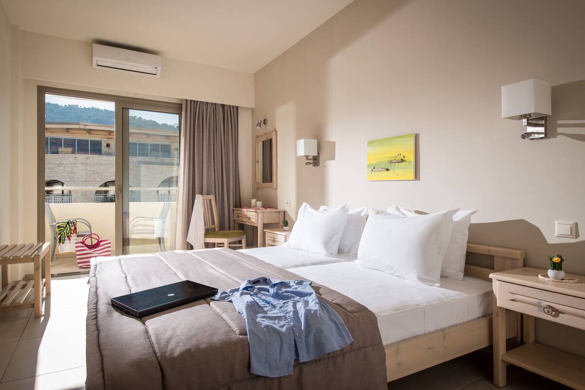 Een hotelkamer met een bed, een bureau, een stoel, een raam met uitzicht en een balkon.