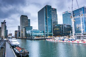 Eine Skyline am Wasser mit modernen Wolkenkratzern, einer Marina mit Booten und einer Brücke, die die Gebäude verbindet.
