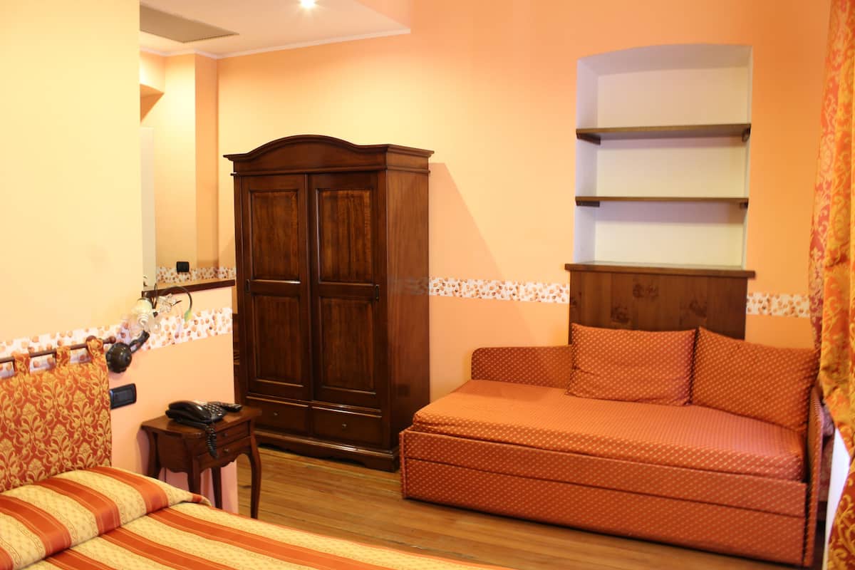 Une chambre à coucher comprenant un lit, un canapé, une armoire et une petite table.
