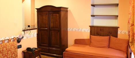 A bedroom with a bed, a sofa, a wardrobe, and a small table.