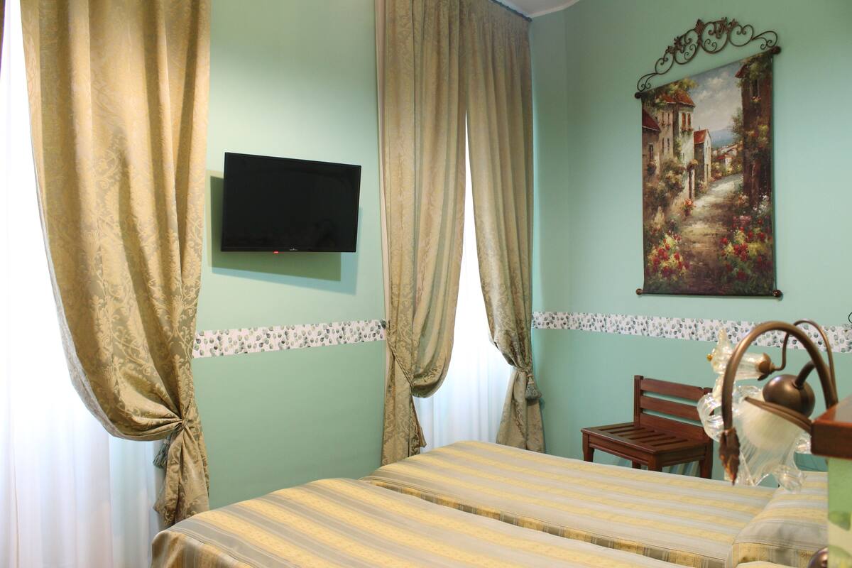 Une chambre avec un lit, une télévision et un tableau au mur.
