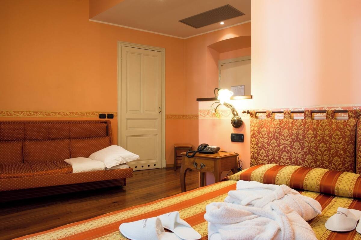 Une chambre d’hôtel comprenant un lit, un canapé, un bureau avec un téléphone et un miroir.