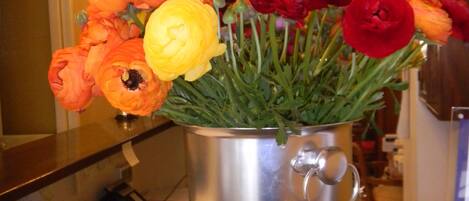 A metal pot with a bouquet of orange, yellow, and red flowers on a wooden surface.