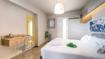 Una habitación de hotel con una cama, un escritorio con silla, un espejo y un aire acondicionado de pared.