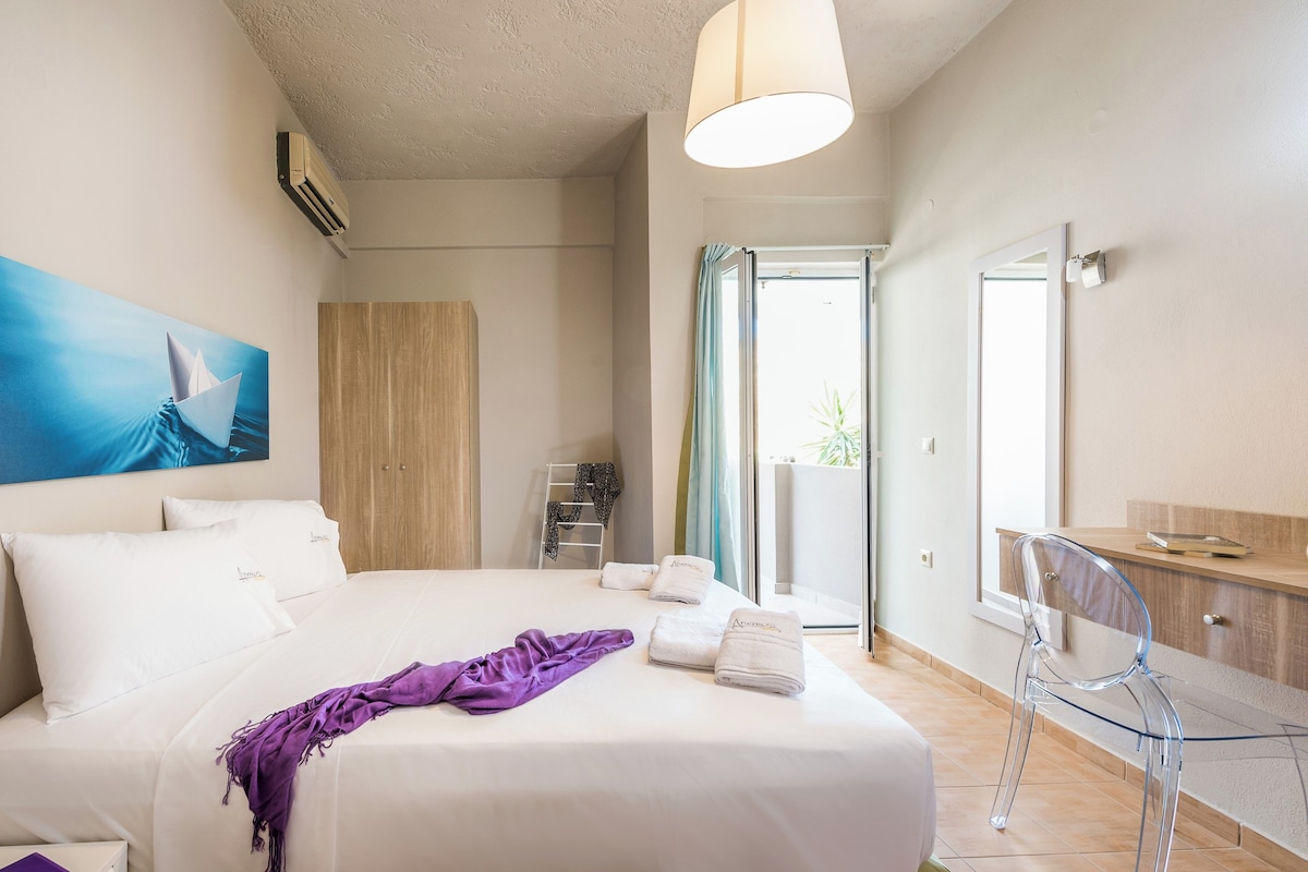 A hotel room with a bed, a bathroom, a balcony, and a view of the outside.