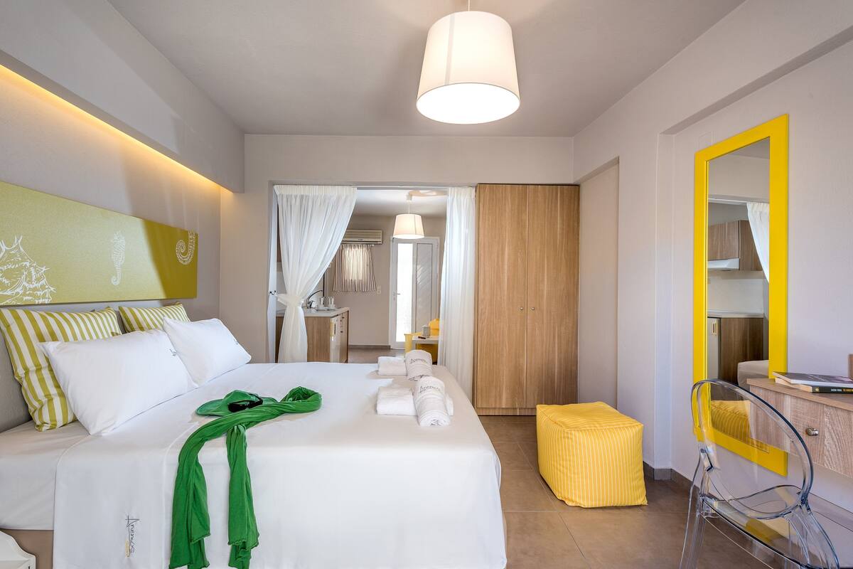 Una habitación de hotel con una cama, un espejo, una silla y una mesita.