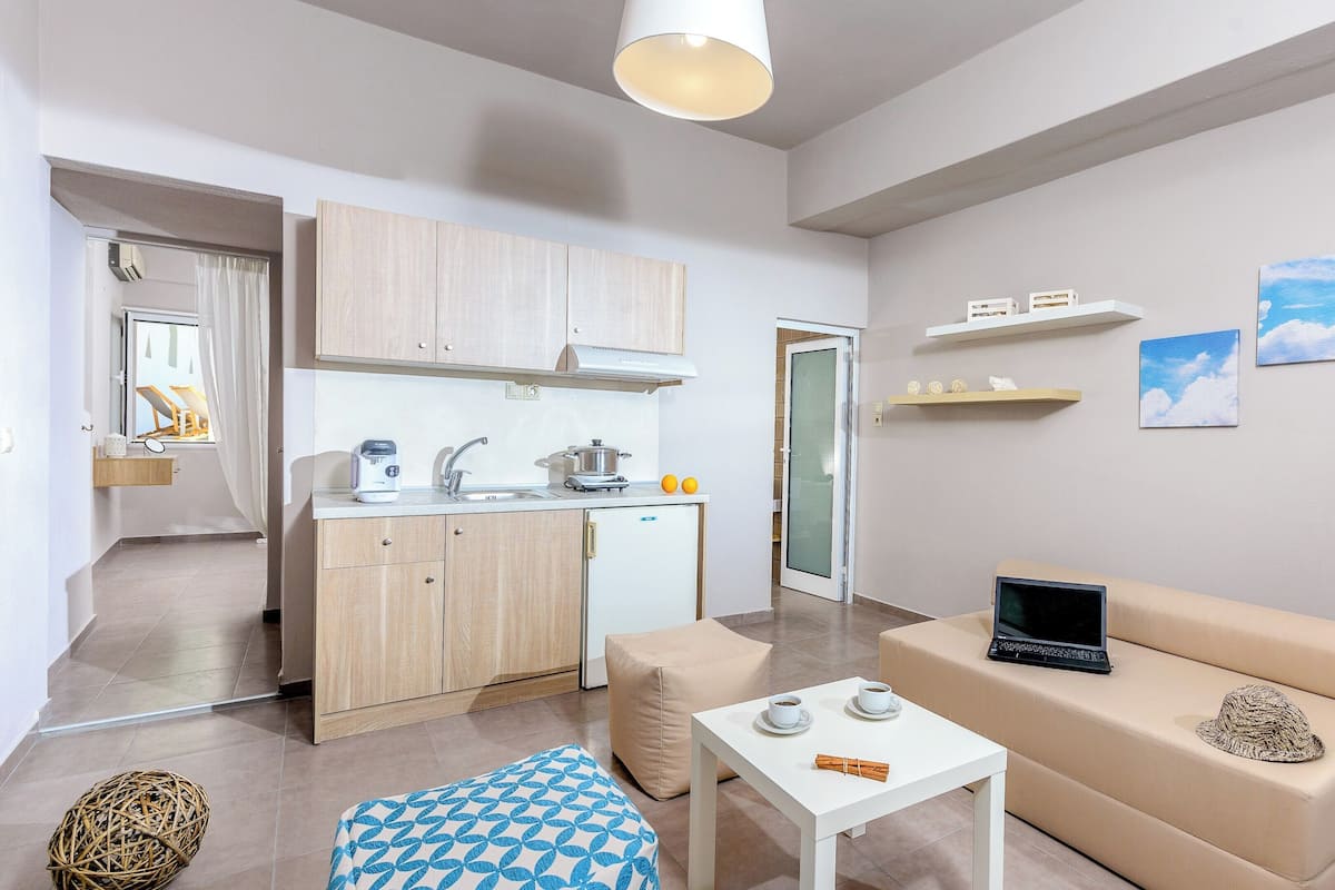 Un espacio habitable compacto con kitchenette, un sofá, una mesa de centro y una computadora portátil.