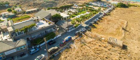 An aerial view of a coastal area with a row of buildings, a parking lot, and a beach.