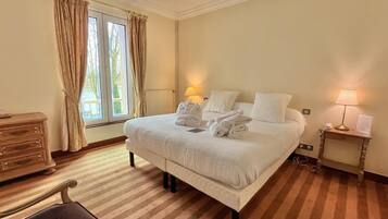 Quarto de hotel com uma cama grande, duas luminárias de cabeceira, uma mesa de cabeceira de madeira, uma escrivaninha e uma cadeira.