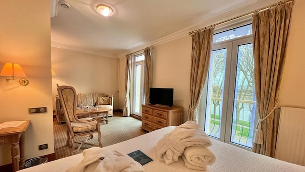 A hotel room with a bed, a desk, a chair, a TV, and a window with curtains. - Hôtel du Rivage (Gien)