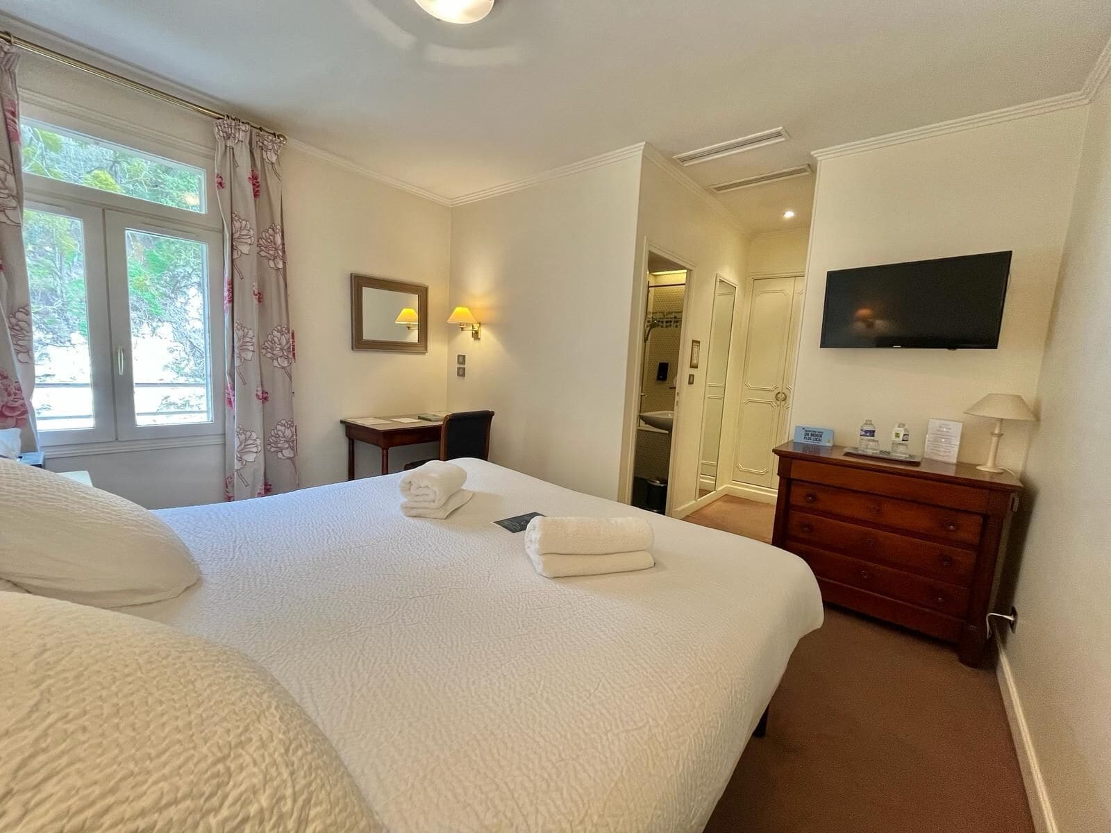Una habitación de hotel con una cama grande, un escritorio, un televisor y un armario.