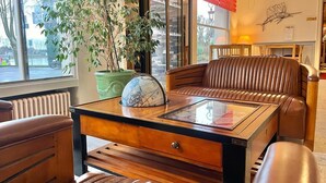 A cozy seating area with leather sofas and a wooden coffee table, a potted plant, and a globe. - Hôtel du Rivage (Gien)