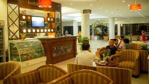 Un vestíbulo de hotel con una zona de bar, arreglos de asientos y una pantalla de televisión.