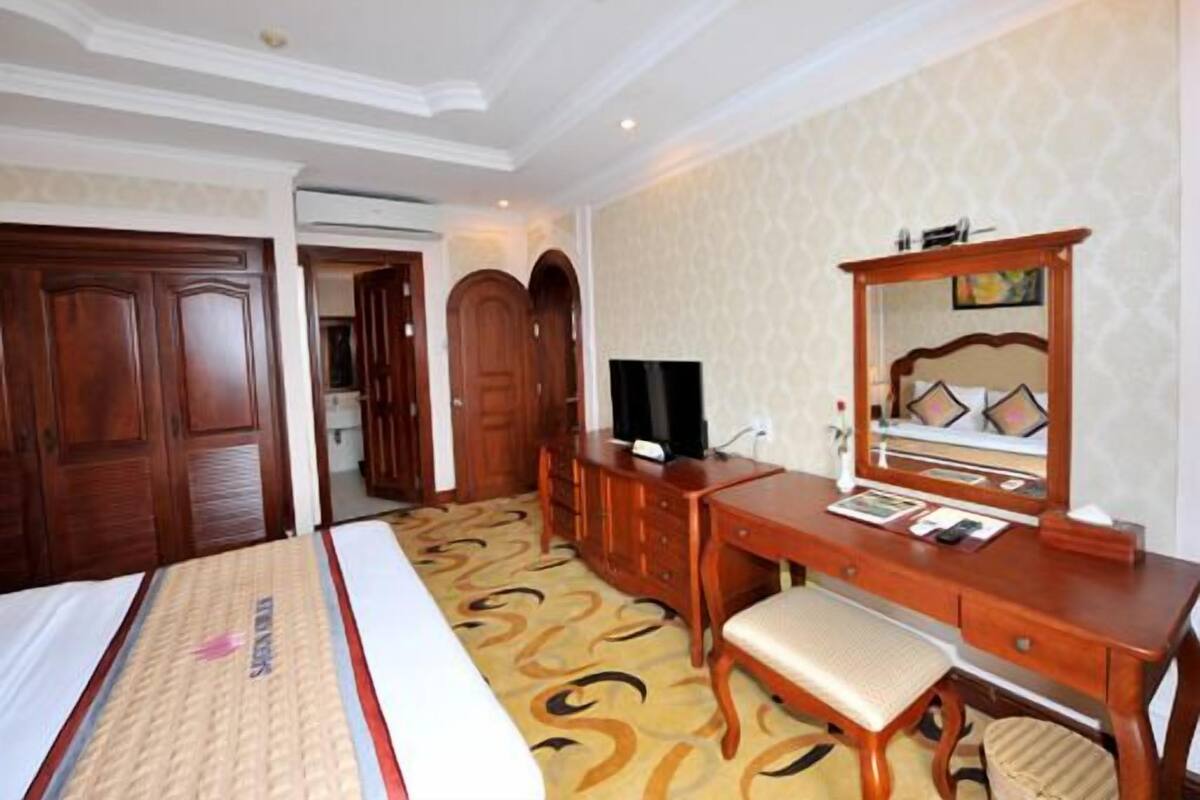 Une chambre d’hôtel comprenant un lit, un bureau avec une chaise, une télévision et une armoire.
