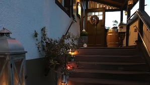 A wooden staircase leading to a door with a glass panel, surrounded by potted plants and a lantern. - Hotel Landgasthof Sonne (Mahlberg)