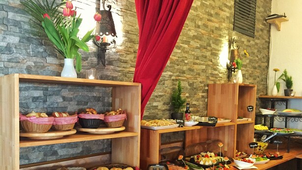 A buffet with various food items, including bread, pastries, and salads, displayed on wooden shelves and tables. - Hotel Landgasthof Sonne (Mahlberg)