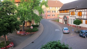 A street with a car parked on the side, a building with a half-timbered facade, and a tree-lined sidewalk. - Hotel Landgasthof Sonne (Mahlberg)