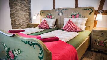 Ein Bett mit blumigem Kopfteil und Kissen, Nachttische aus Holz sowie eine Steinwand.
