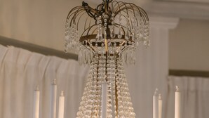 A chandelier with multiple candle-like fixtures and crystal decorations. - Hotel Vännäs (Vannas)