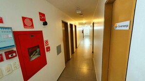 A hotel corridor with red fire safety equipment, a sign for Governance, and a fire alarm panel. - Bluemar Hotel (Maceió)
