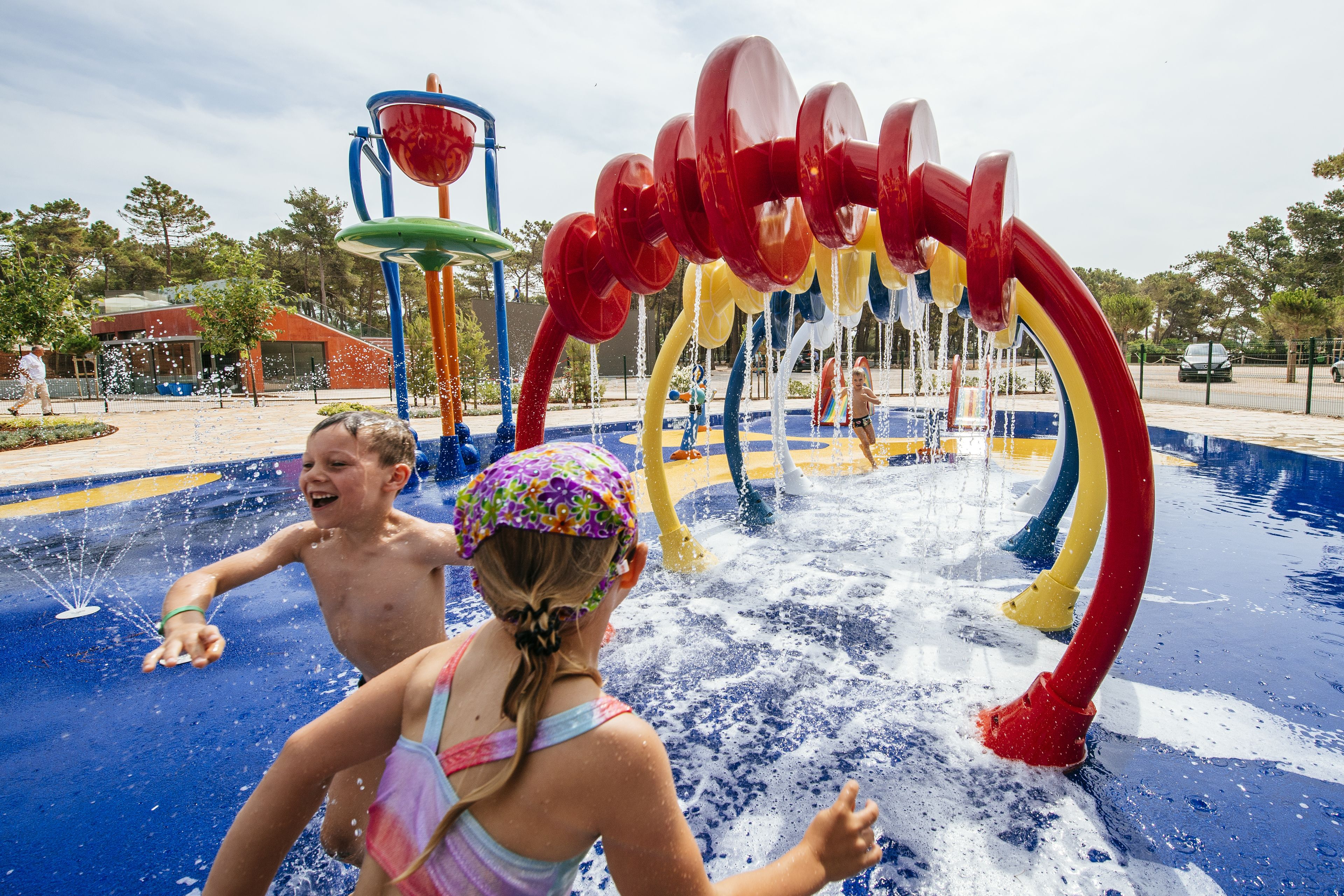 Un parc aquatique avec une aire de jeux aquatique colorée et un bâtiment en arrière-plan.