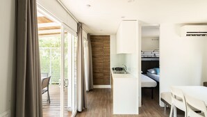 Habitación de hotel compacta con kitchenette, zona de comedor y puerta corrediza de vidrio que da a un patio exterior.