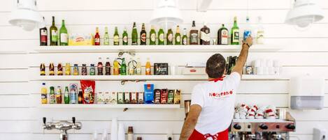 A person stocking shelves with various beverages and snacks in a well-organized kitchen area.