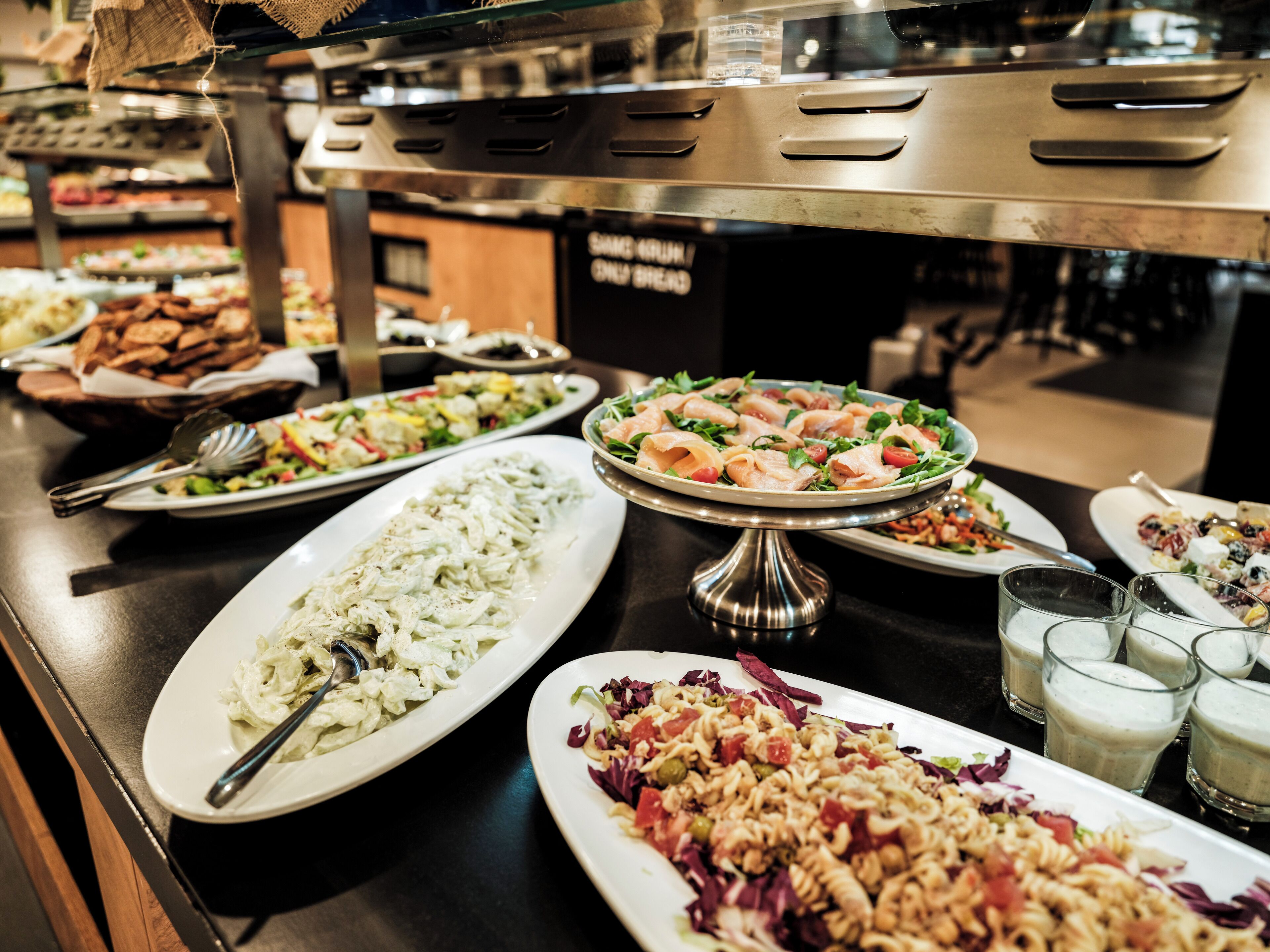 A buffet with various dishes including pasta, salads, and other prepared foods.