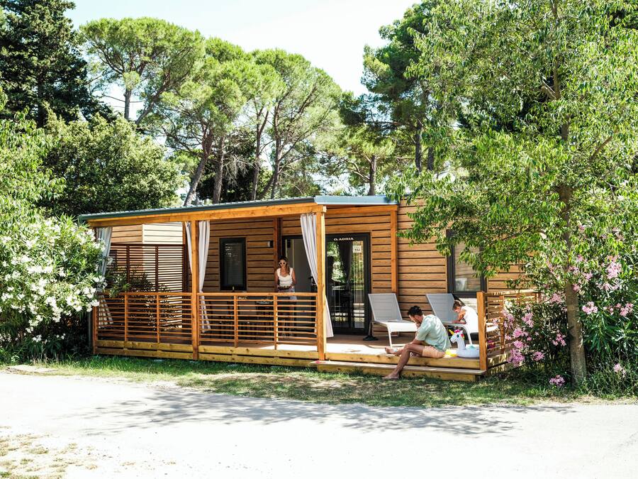 Une cabane en bois avec un porche, une petite terrasse et un espace extérieur aménagé et abrité.