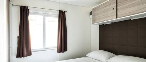 A bedroom with a bed, curtains, and a headboard.