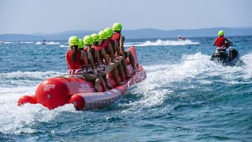 Eine Gruppe von Menschen auf einer roten Luftinsel mit Helmen, die von einem Jetski gezogen werden.