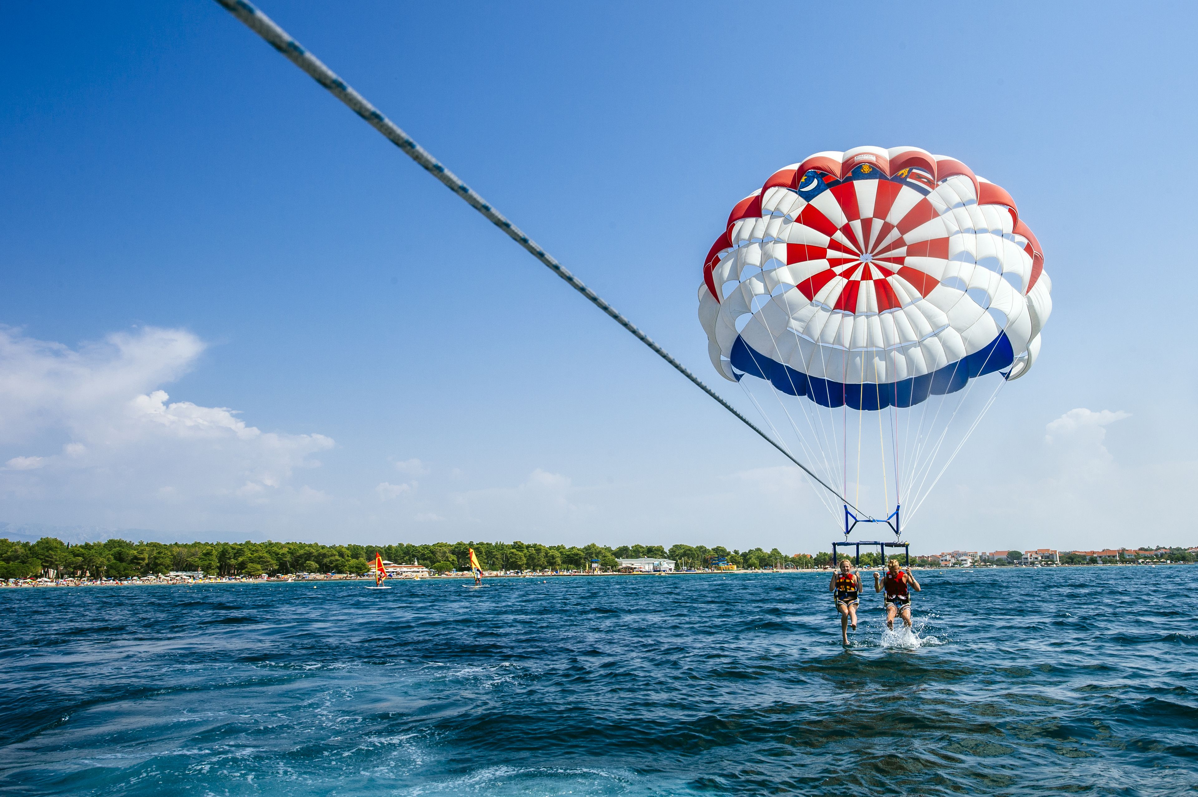 Une activité de parachute ascensionnel au-dessus d’une étendue d’eau, par temps clair.