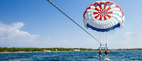 Une activité de parachute ascensionnel au-dessus d’une étendue d’eau, par temps clair.