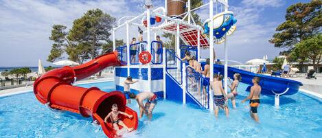 A water park with a red water slide, blue water play area, and a pool.