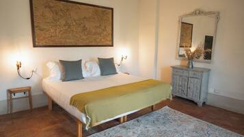 Un dormitorio con cama, lámparas de noche, mesita de noche, cómoda y un cuadro grande enmarcado en la pared.