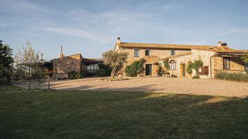 Une ferme en pierre avec une allée en gravier et une pelouse verdoyante.