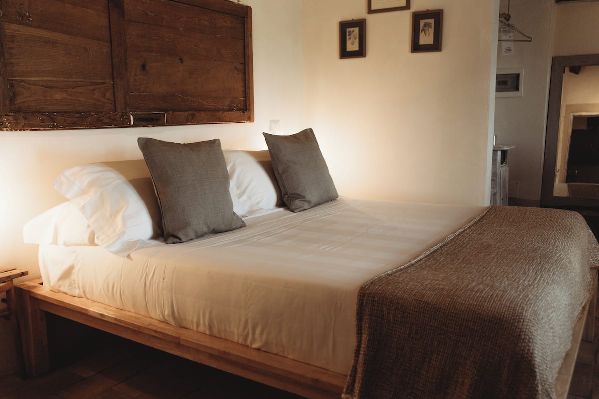Ein Einzelbett mit Holzrahmen, weißer Bettwäsche und zwei Kissen.