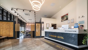 A reception area with a reception desk labeled "Sunrise Hotel," a seating area with wooden partitions, and a staircase leading to an upper level. - Sunrise Hotel Jungmun (Seogwipo)