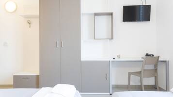 Hotellihuone, jossa on kaksi sänkyä, työpöytä, tuoli, televisio ja vaatekaappi.