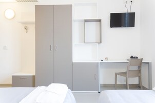 Camera d'albergo con due letti, una scrivania, una sedia, una TV e un armadio.