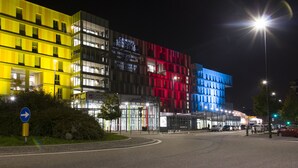 A multi-story building with illuminated signage, a roundabout, and a street with vehicles. - Hotel Campus Sanpaolo (Turin)